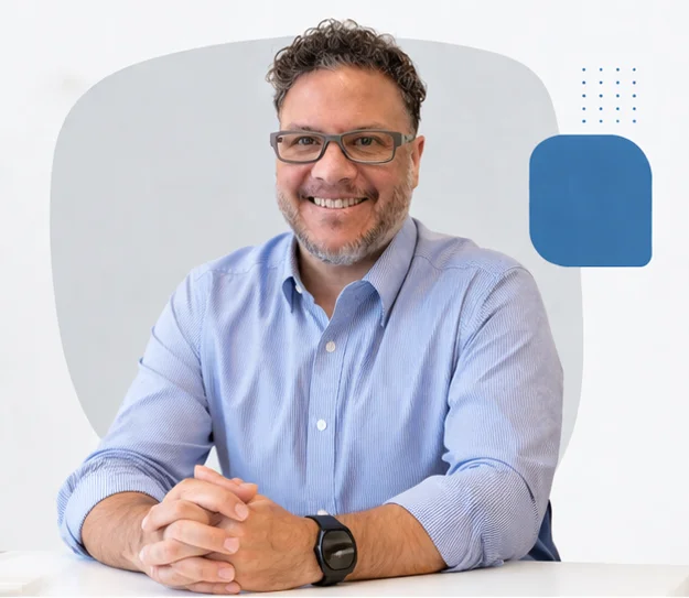 Victor Alvarez sitting on a desk smiling looking at the camera